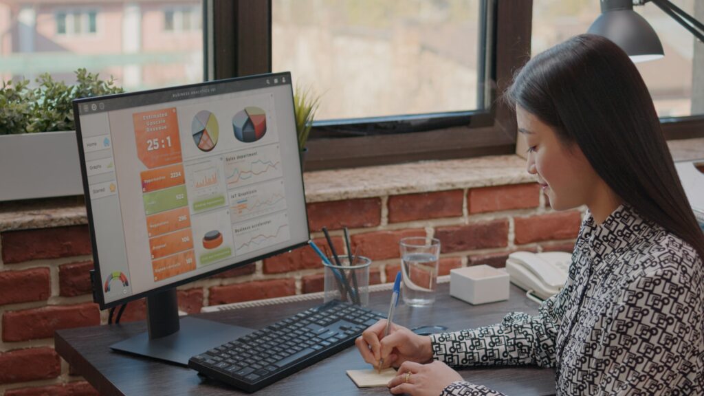 Woman analyzing business data on computer, writing notes - MaherTech Inc (Animation)