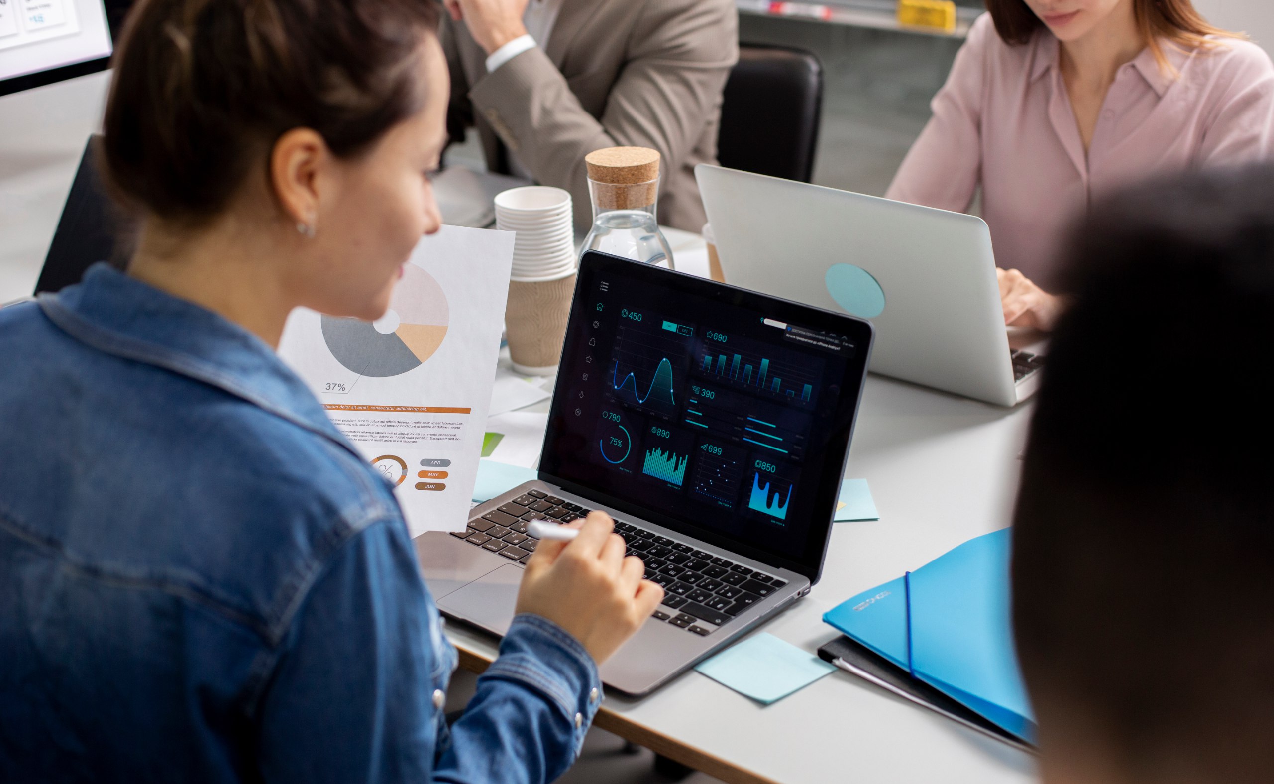 About us - Woman analyzing data on a laptop in a meeting - MaherTech Inc (Resources)